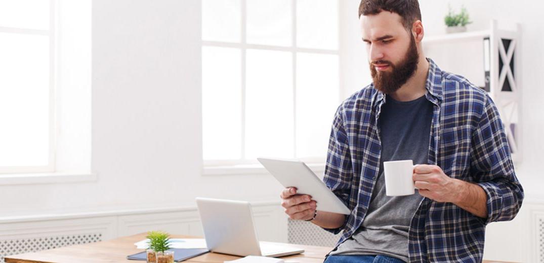 A bearded man uses a tablet to log into a Zoom call with a Patelco Insurance advisor.